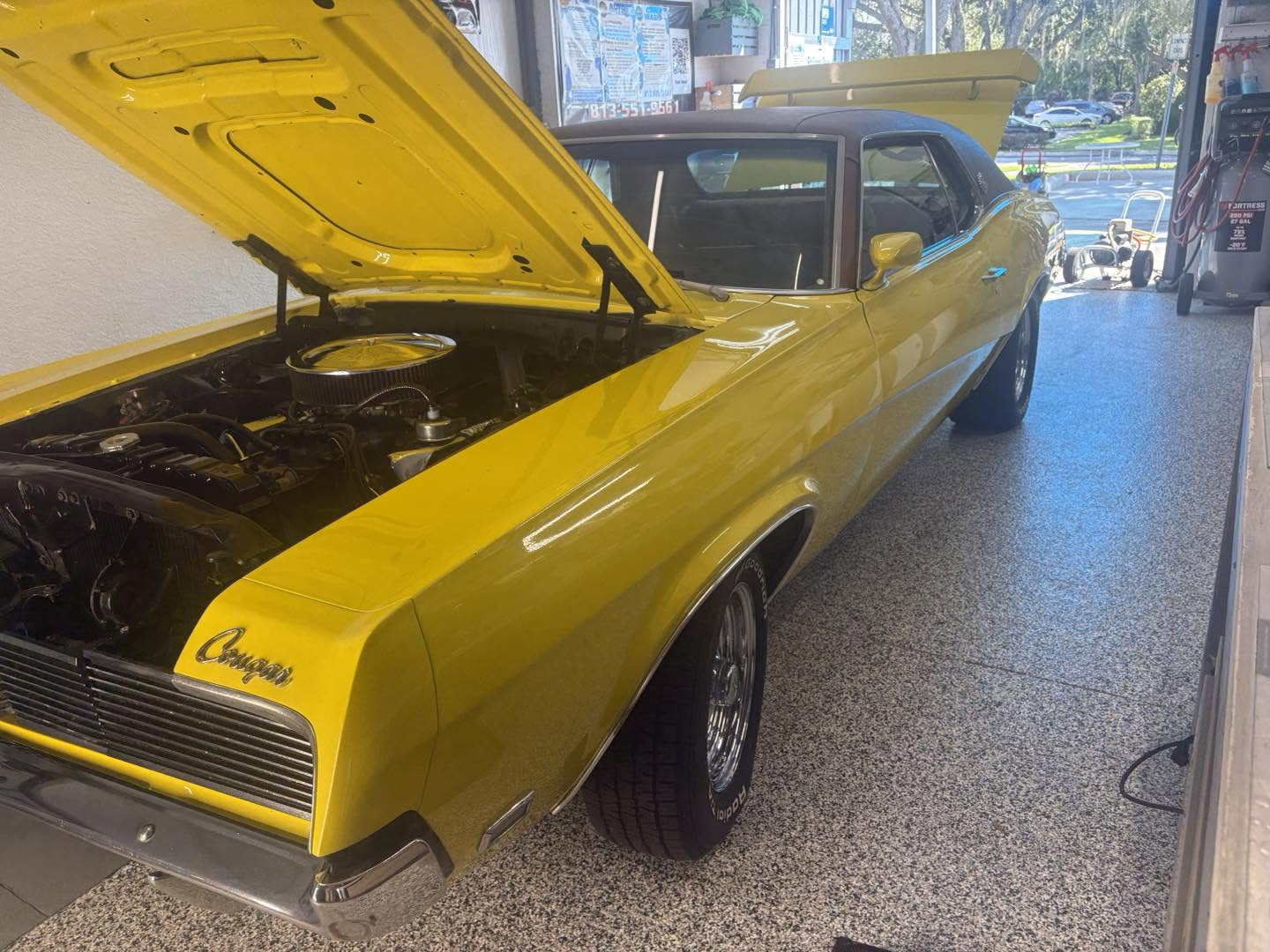 Yellow classic Mercury Cougar with hood open inside Brilliant Shine studio